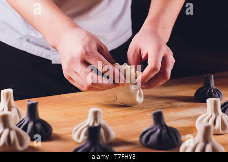 Nazionale cucina georgiana Khinkali sfondo metallico cuoco prepara khinkali cucina vista dall'alto la carne cruda piatto di pasta alimentare cruda stand cinese di vendita Foto Stock