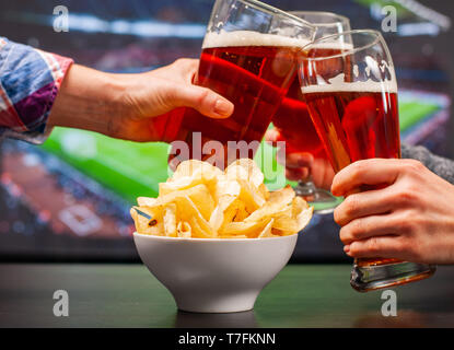 Happy amici o gli appassionati di calcio sono il tintinnio di bicchieri di birra e guardare il calcio Foto Stock