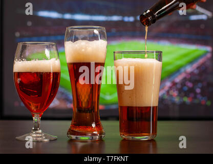 Bicchieri da birra nella parte anteriore della tv, calcio a casa, i tifosi di calcio Foto Stock