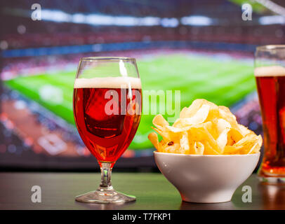 Bicchieri da birra e patatine nella parte anteriore della tv, calcio a casa, i tifosi di calcio Foto Stock