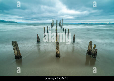 Come una strada per l'inferno un molo vecchio all'interno del lago di acque sotto un drammatico cielo nuvoloso e venti alti. I vecchi pali in legno ancora lotta contro il tempo Foto Stock