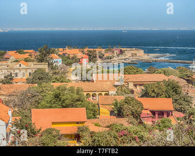 Gorea, Senegal - Febbraio 2, 2019: Vista di case con il tetto rosso sull'isola di Goree con Dakar in background. Gorée. Dakar, Senegal. L'Africa. Foto Stock