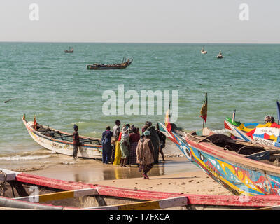 Nianing, Senegal - Gennaio 2, 2019: i pescatori la raccolta di pesce di legno colorato barca fisher permanente sulla spiaggia. Africa Foto Stock