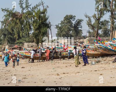 Nianing, Senegal - Gennaio 2, 2019: i pescatori la raccolta di pesce di legno colorato barca fisher permanente sulla spiaggia. Africa Foto Stock