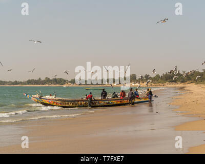 Nianing, Senegal - Gennaio 2, 2019: i pescatori la raccolta di pesce di legno colorato barca fisher permanente sulla spiaggia. Africa Foto Stock