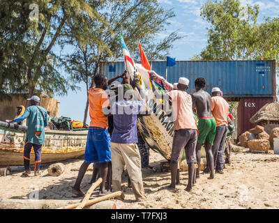 Nianing, Senegal - Gennaio 2, 2019: i pescatori la raccolta di pesce di legno colorato barca fisher permanente sulla spiaggia. Africa Foto Stock