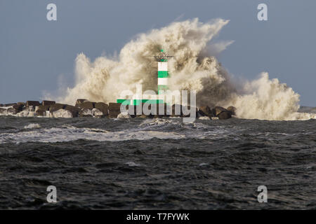 Grandi onde che si schiantano contro il faro di Punta del molo di ijmuiden, Paesi Bassi, durante la grave tempesta oltre il mare del Nord. Foto Stock