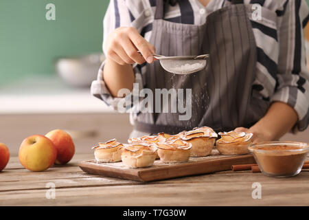 Donna che rendono Apple roses da pasta sfoglia in cucina Foto Stock