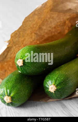 Zucchina organico in un sacchetto di carta su legno grigio. Riciclare la confezione del concetto. No dei rifiuti di plastica. Foto Stock