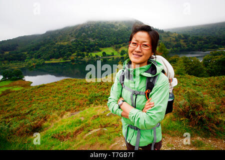 Sorridente East Asian Woman Hiking nel Lake District, Cumbria, Regno Unito. Foto Stock