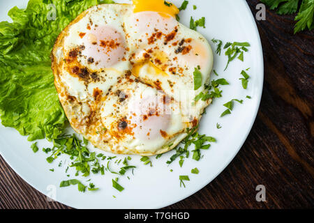 Piatto di laici gustosa colazione su cemento grigio sfondo tabella. Uova fritte, micro verdi, pomodori freschi nella piastra, vista dall'alto. Pulire mangiare, dieta Foto Stock