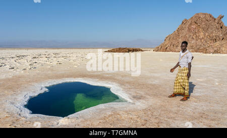 Lontano soldato nei pressi di un laghetto salato nella pianura di sale nella depressione di Danakil in Etiopia in Africa nella stagione invernale. Foto Stock