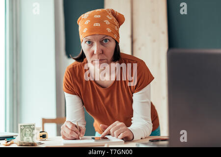 Falegname femmina con il fazzoletto di testa facendo il calcolo finanziario in falegnameria officina di falegnameria Foto Stock