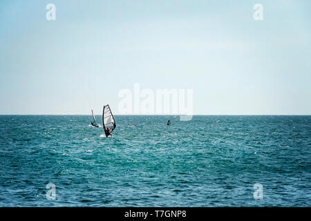 Mui Ne, Vietnam. Man Riproduci wind surf sport in mare sotto il vasto cielo blu Foto Stock