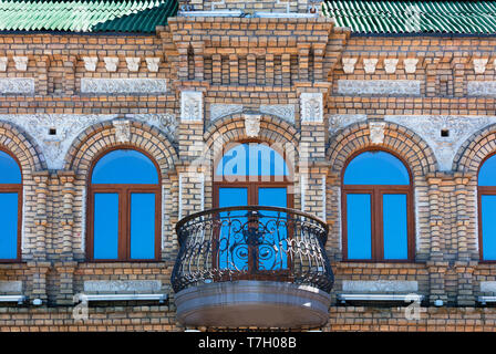 Elementi figurati di una casa di mattoni, un balcone in ferro battuto, reticolare un cielo blu riflessa nelle finestre in legno creano uno splendido complesso architettonico del Foto Stock