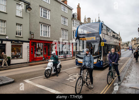 Oxford, Regno Unito - Mar 3, 2017: pendolari tra uomini e donne sul ciclomotore, ciclisti su piste dedicate in attesa con double-decker bus a luce rossa a Oxford, su High street Foto Stock