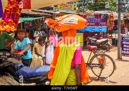 Scena di strada in Shahpura, un quartiere Dindori cittadina nel Madhya Pradesh (India centrale), una donna locale porta un pacchetto sulla sua testa Foto Stock