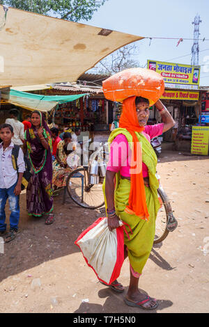 Scena di strada in Shahpura, un quartiere Dindori cittadina nel Madhya Pradesh (India centrale), un locale vecchia donna porta un pacchetto sulla sua testa Foto Stock