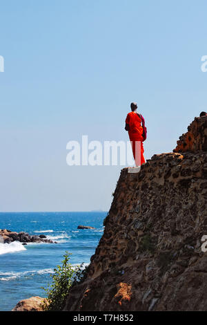 Monaco buddista si erge sulla roccia e orologi al mare, una nave ci va, Sri Lanka Foto Stock