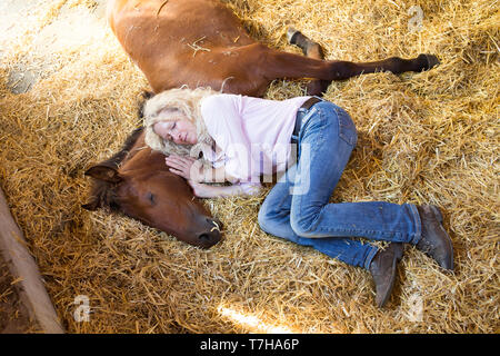 Sport iberica cavallo. Andrea Jaenicke e bay puledro in appoggio insieme in una stalla. Germania Foto Stock