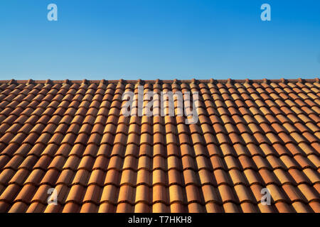 Tetto arancione casa tegola contro il cielo blu e la calda luce del sole in estate. alloggiamento e immobiliare di concetto. Foto Stock