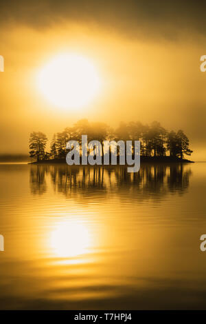 Luce di Sunrise e nebbiosa aria sopra il lago Jonsvatnet vicino a Trondheim, Norvegia. Vista sulla piccola isola. Foto Stock