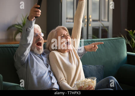 Emozionato Coppia matura, l uomo e la donna guardando la partita di calcio, celebrando la vittoria Foto Stock