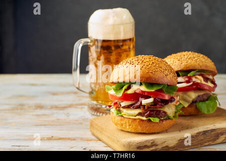 Due grandi hamburger e pinta di birra sul vecchio tavolo in legno Foto Stock