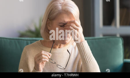 Close up infelice dai capelli grigi donna matura che soffrono di affaticamento degli occhi Foto Stock