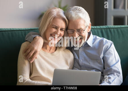 Felice di ridere coppia marito e moglie si divertono con il computer portatile Foto Stock