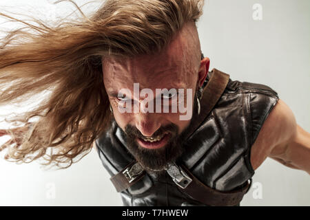 Dio del tuono. Bionda capelli lunghi e muscolare modello maschile in pelle Viking's costume con il grande martello di Thor cosplaying isolato su bianco di sfondo per studio. Fantasy warrior, antico concetto di battaglia. Foto Stock