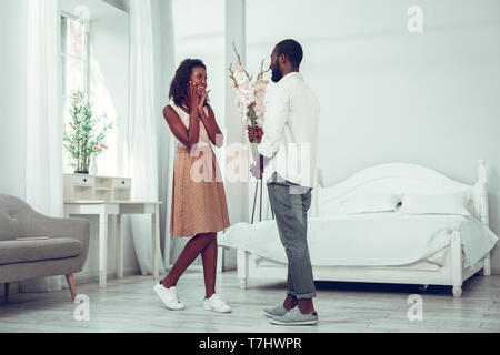 Scioccato donna ottenere fiori dal suo bel marito attraente Foto Stock