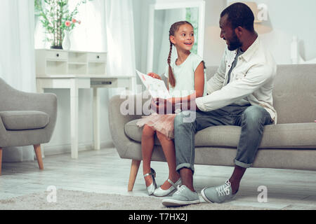 Bel papà sorridente guardando il disegno realizzato da sua figlia. Foto Stock