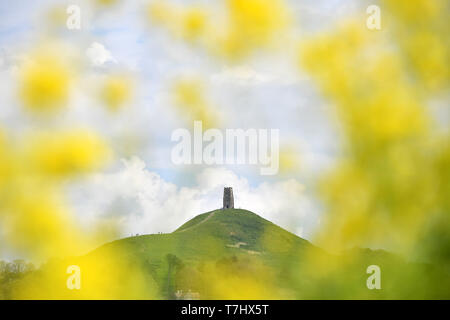 Cielo nuvoloso visto attraverso un campo di colza a Glastonbury Tor in Somerset, come la Gran Bretagna è impostata per essere colpito con temporali e piogge di questa settimana. Foto Stock