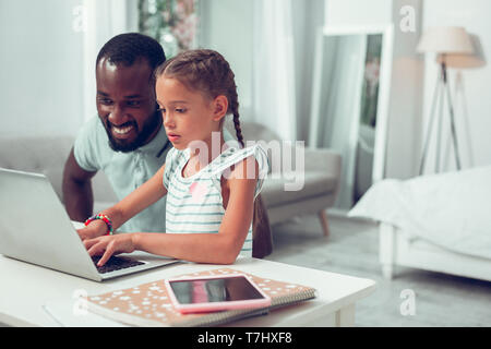 Focalizzato ragazza afro-americana con trecce digitando su una tastiera portatile Foto Stock