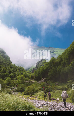 Una magica vista del boscoso monte con cielo blu e nuvole massicce. Un gruppo di escursionisti è nella foresta. Foto Stock