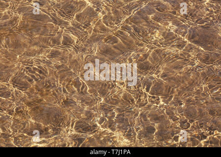 Mare cristallino e parte inferiore sabbiosa sfondo. Sabbia attraverso la trasparente acqua texture. Foto Stock