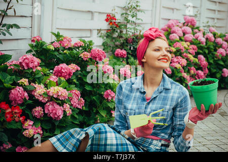 La cura dei fiori e irrigazione. suoli e fertilizzanti. Fiori di serra. donna felice giardiniere con fiori. hydrangea. La primavera e l'estate. donna cura di Foto Stock