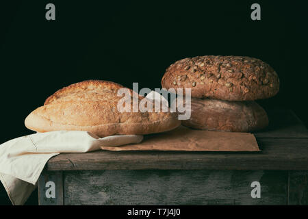 Tre forme di pane cotto al forno del pane su una tavola di legno, prodotto con zucca e semi di girasole Foto Stock