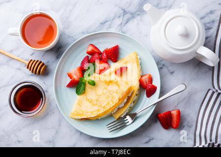 Crepes, thin pancake con crema di formaggio e ricotta e fragole fresche. Sfondo marmo. Vista dall'alto. Foto Stock