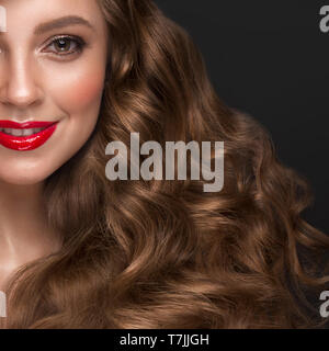 Bellissimi i capelli castani ragazza con una perfettamente si arriccia capelli, labbra rosse e classic per il make-up. Bellezza Viso e capelli. Foto Stock