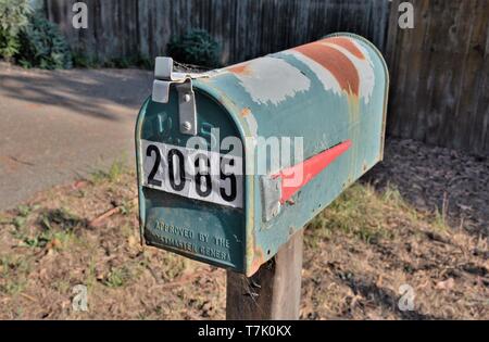 Arrugginimento noi la cassetta postale con numero su di esso sulla strada rurale in America USA USA il servizio postale Foto Stock