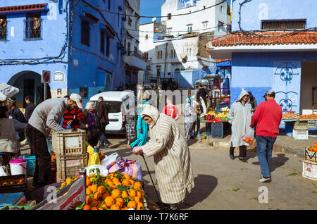 Chefchaouen, Marocco : un anziano uomo marocchino indossando un djellaba negozi di frutta e verdura presso Plaza Bab Suk piazza del mercato, nel blu-lavato med Foto Stock