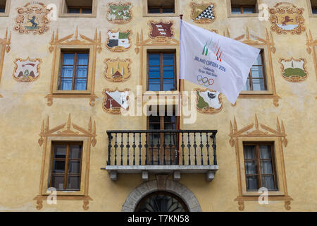 Bandiera di Milano Cortina città candidata per i Giochi Olimpici Invernali 2026 su un edificio storico a Cortina d'Ampezzo, Italia Foto Stock