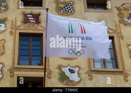Bandiera di Milano Cortina città candidata per i Giochi Olimpici Invernali 2026 su un edificio storico a Cortina d'Ampezzo, Italia Foto Stock