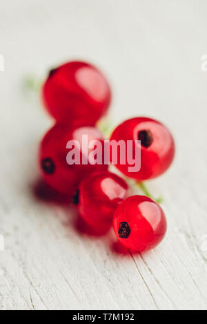 Grappolo di ribes rosso oltre alla luce una superficie di legno Foto Stock