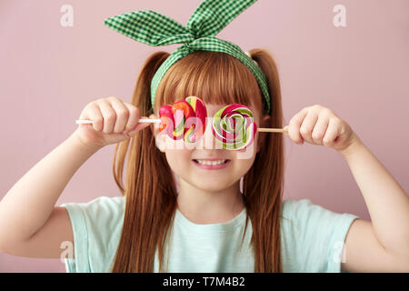Carino bambina con connettori lollipop sul colore di sfondo Foto Stock