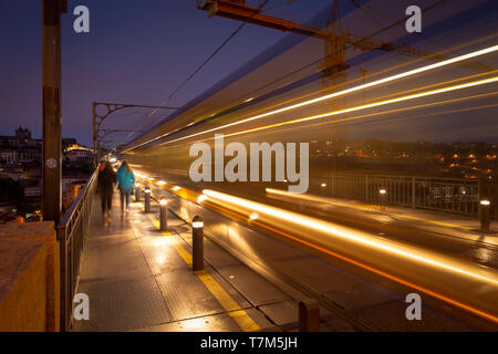 Porto treno della metropolitana andando lungo la parte superiore del ponte Dom Luis bridge di notte, offuscata motion e illuminazione Foto Stock
