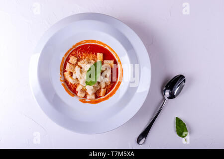 Crema di pomodoro zuppa con cracker in una piastra bianca su sfondo bianco. Foto Stock