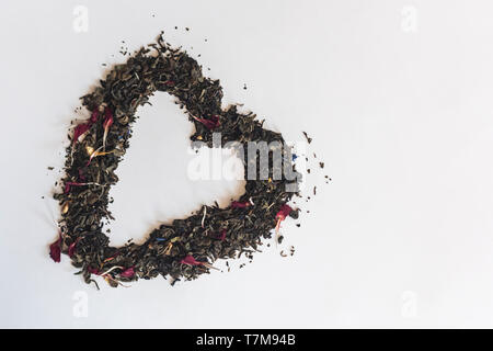 Forma di cuore realizzato con una miscela di una varietà di tè essiccate su sfondo bianco Foto Stock